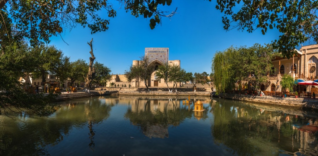 Lyabi-Hauz pond reflecting historic madrasas and mulberry trees in Bukhara