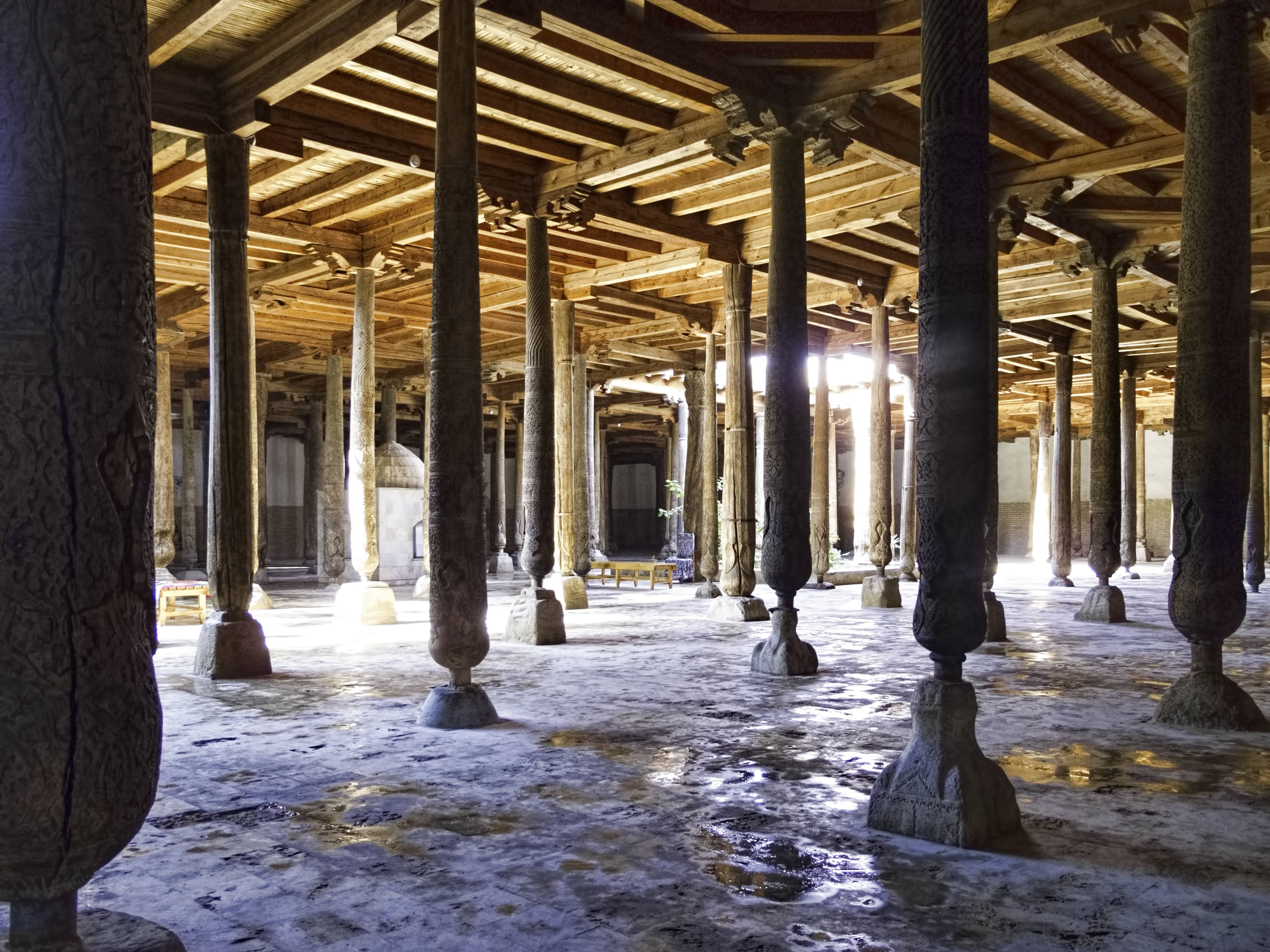 Sunlight filtering through roof light wells into the forest of wooden columns in Juma Mosque