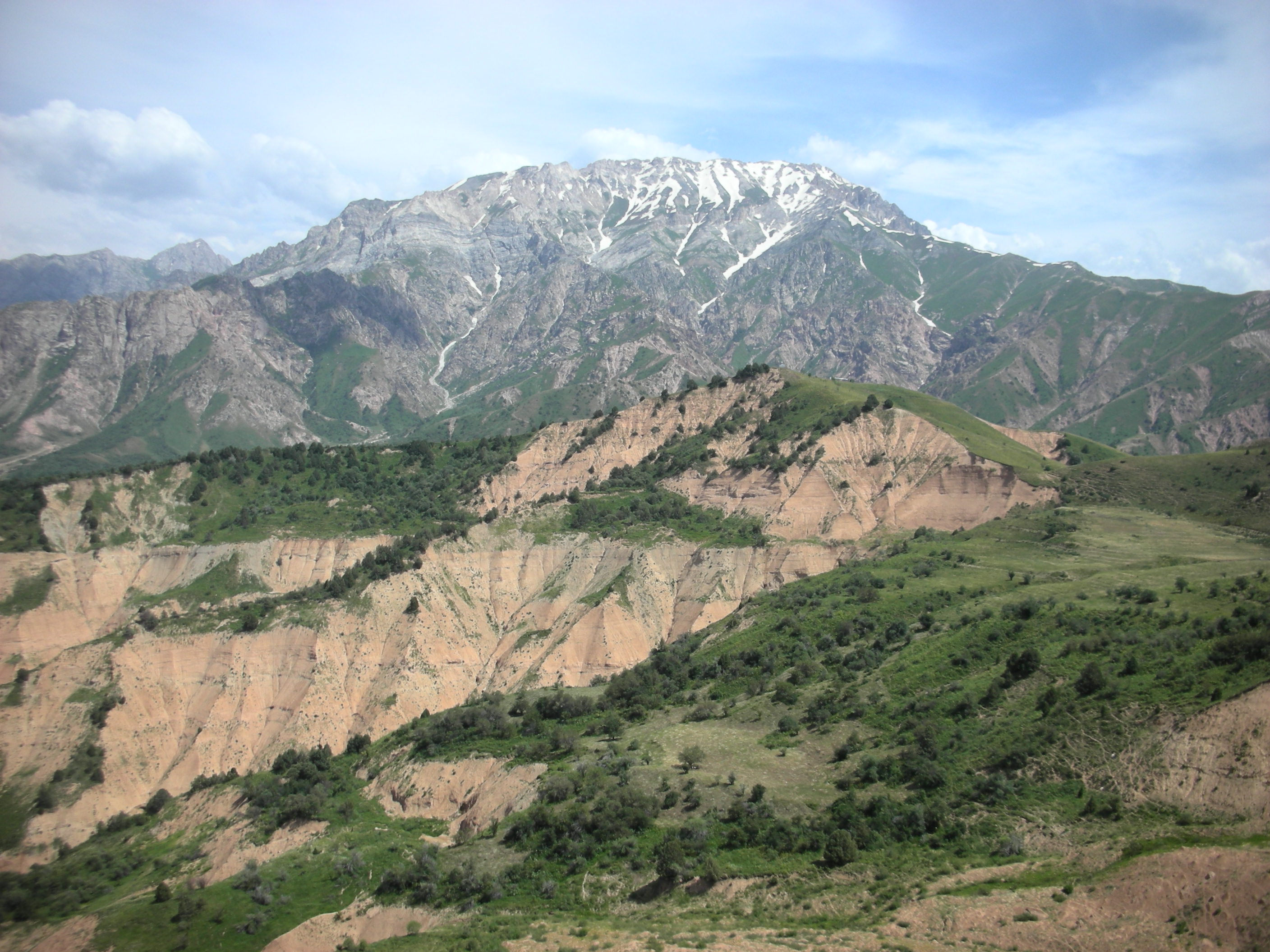 Rugged rocky slopes of Greater Chimgan mountain peak under dramatic alpine skies